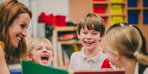 Students laugh while substitute teacher reads to them