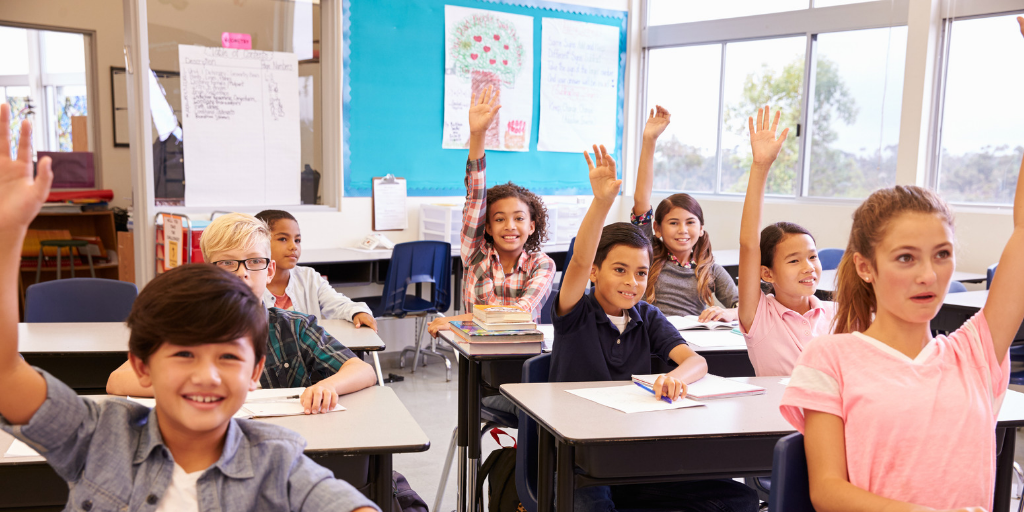 Students raise their hands in a classroom.
